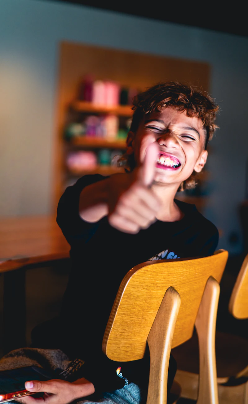 A smiling boy giving a thumbs-up
